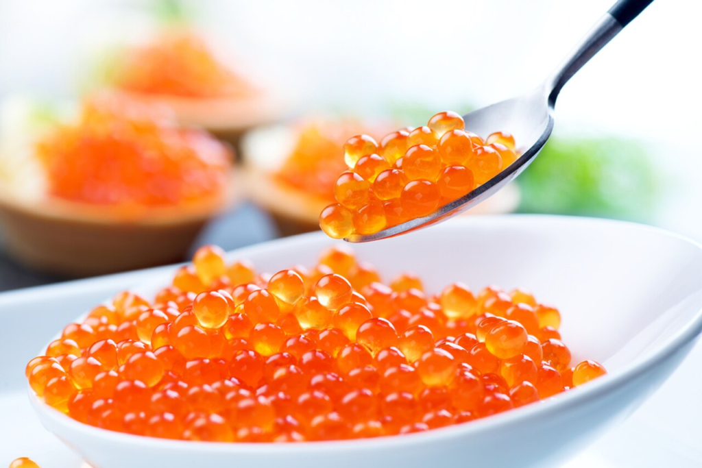 Red caviar being spooned from a dish