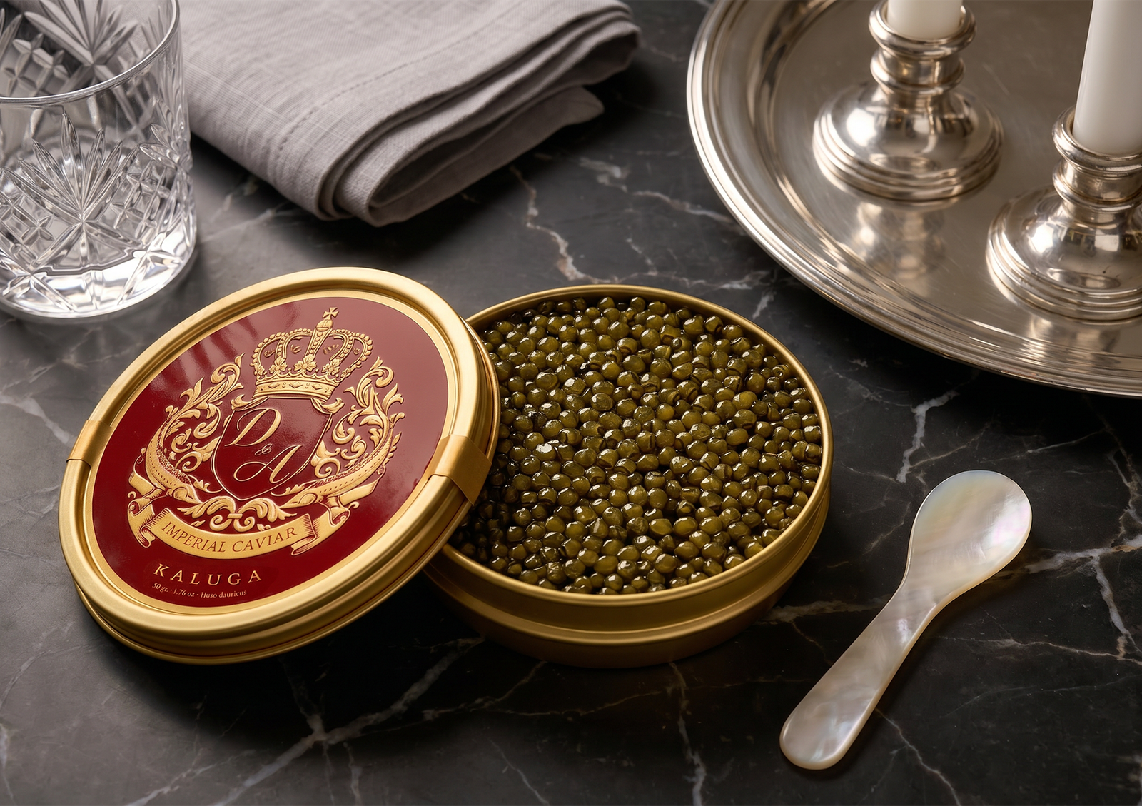 A close-up of an open golden tin of Imperial Kaluga caviar indonesia filled with large, glossy golden-green pearls, elegantly set on a dark marble table next to a mother-of-pearl spoon and silver tableware.